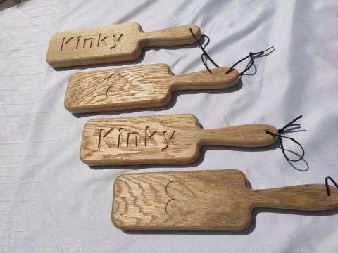 Drewniane packi do klapsów z grawerem „Kinky” i sercem, wykonane z litego dębu, leżące na białym tle – gadżet erotyczny BDSM Drewniane packi do klapsów z grawerem „Kinky” i sercem, wykonane z litego dębu, leżące na białym tle – gadżet erotyczny BDSM
