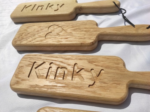 Drewniane packi do klapsów z grawerem „Kinky” i sercem, wykonane z litego dębu, leżące na białym tle – gadżet erotyczny BDSM Drewniane packi do klapsów z grawerem „Kinky” i sercem, wykonane z litego dębu, leżące na białym tle – gadżet erotyczny BDSM