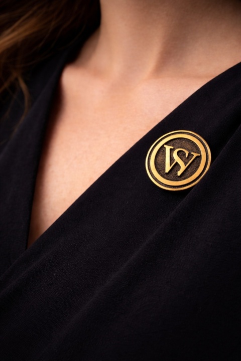 Przypinka SW SassyWorld na czarnej sukience – symbol społeczności